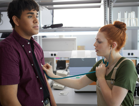 A woman examines a man's chest using a stethoscope.